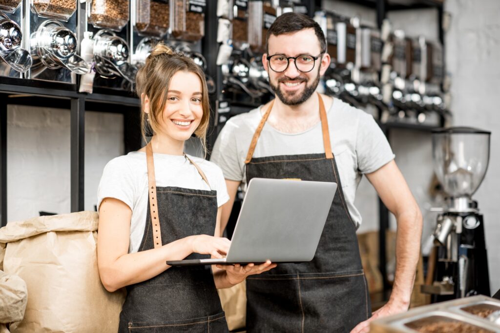 Coffee store owners working with laptop indoors