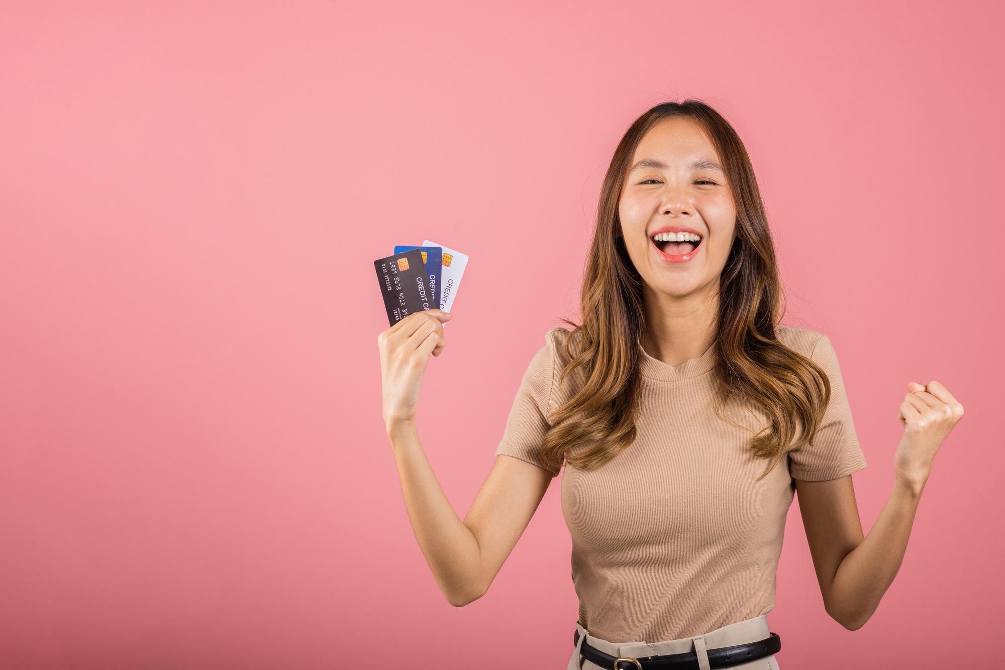 Portrait of Happy excited amazed Asian young woman holding bank card solution in hands in studio
