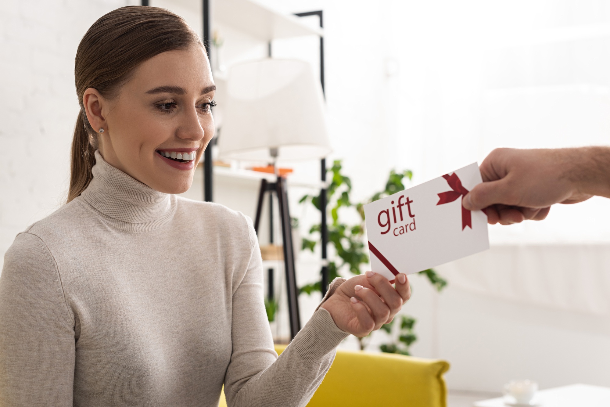 Man giving gift card to beautiful smiling woman at home