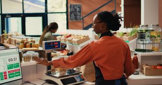 Local merchant placing groceries on scale at cash register Local merchant placing groceries on scale at cash register