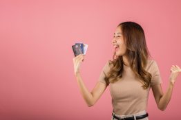 Portrait of Happy excited amazed Asian young woman holding bank card solution in hands in studio Portrait of Happy excited amazed Asian young woman holding bank card solution in hands in studio